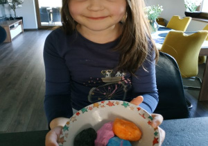 dziewczynka pokazuje rózne kolory masy solnej uformowane w duże jajka